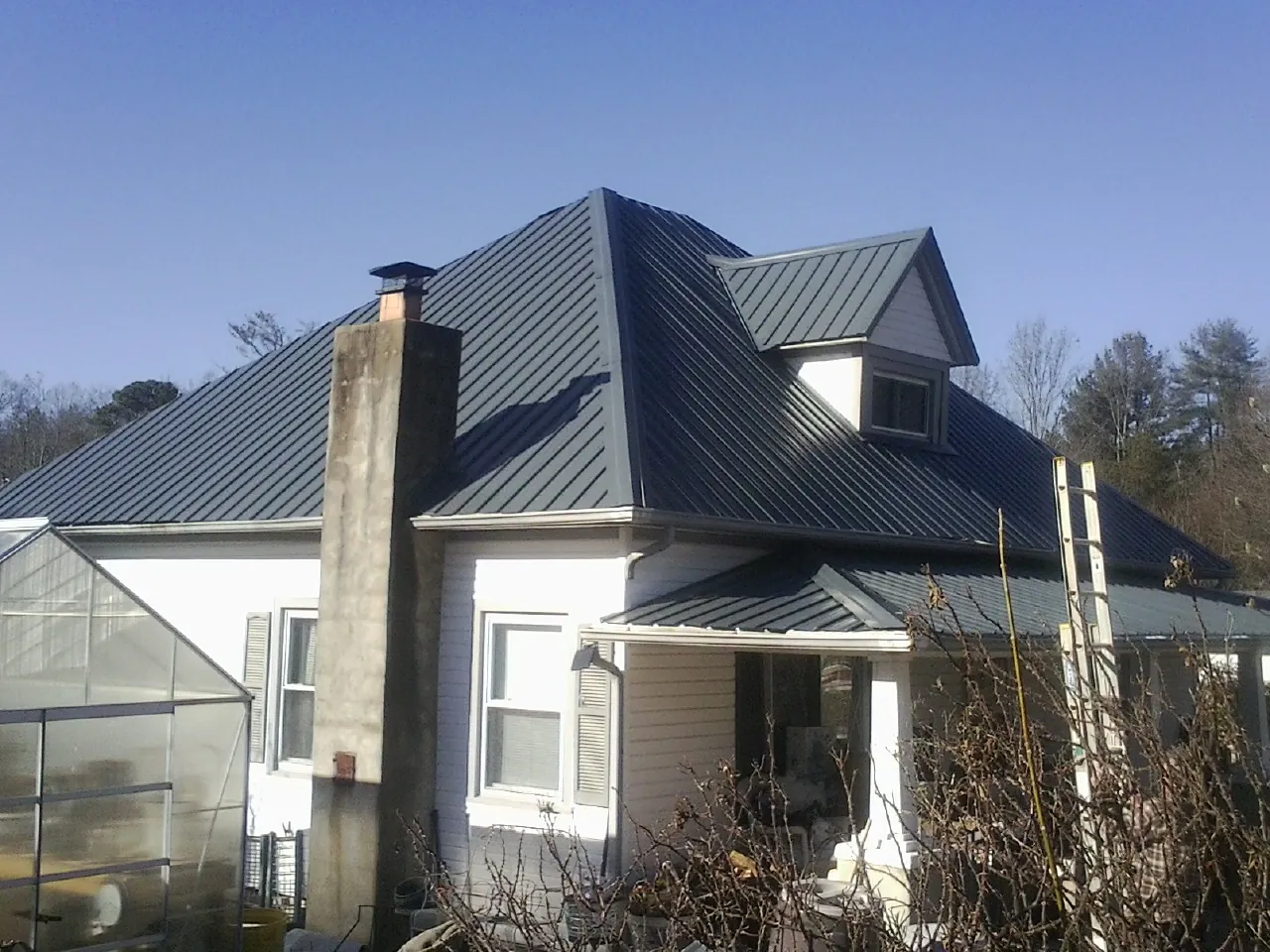 Dark blue standing seam metal roof on a white farmhouse with dormer — Slate & Tile Roof Repair by Roofing Brothers in Burnside