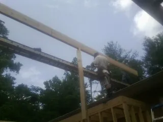 Carpenter setting a ridge beam over a new addition frame — Ice Dam Removal by Roofing Brothers in Burnside