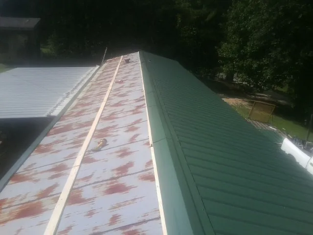 Old rusted panels beside newly installed green metal roofing — Wind Damage Roof Repair by Roofing Brothers in Burnside