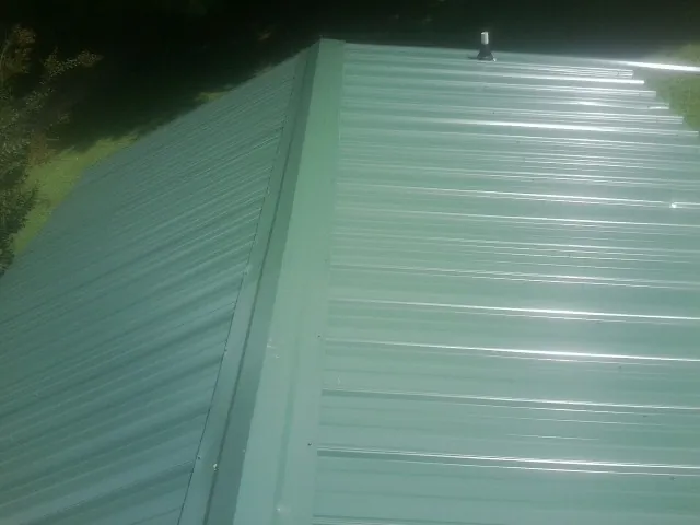 New green metal panels meeting at the ridge of a roof — Flat Roof Repair work by our crew in Burnside