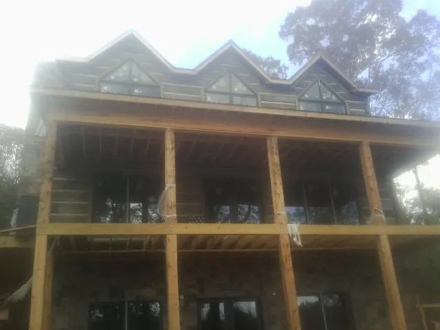 Dormers and porch framing on a large log home under construction — Roof Coating work by our crew in Burnside