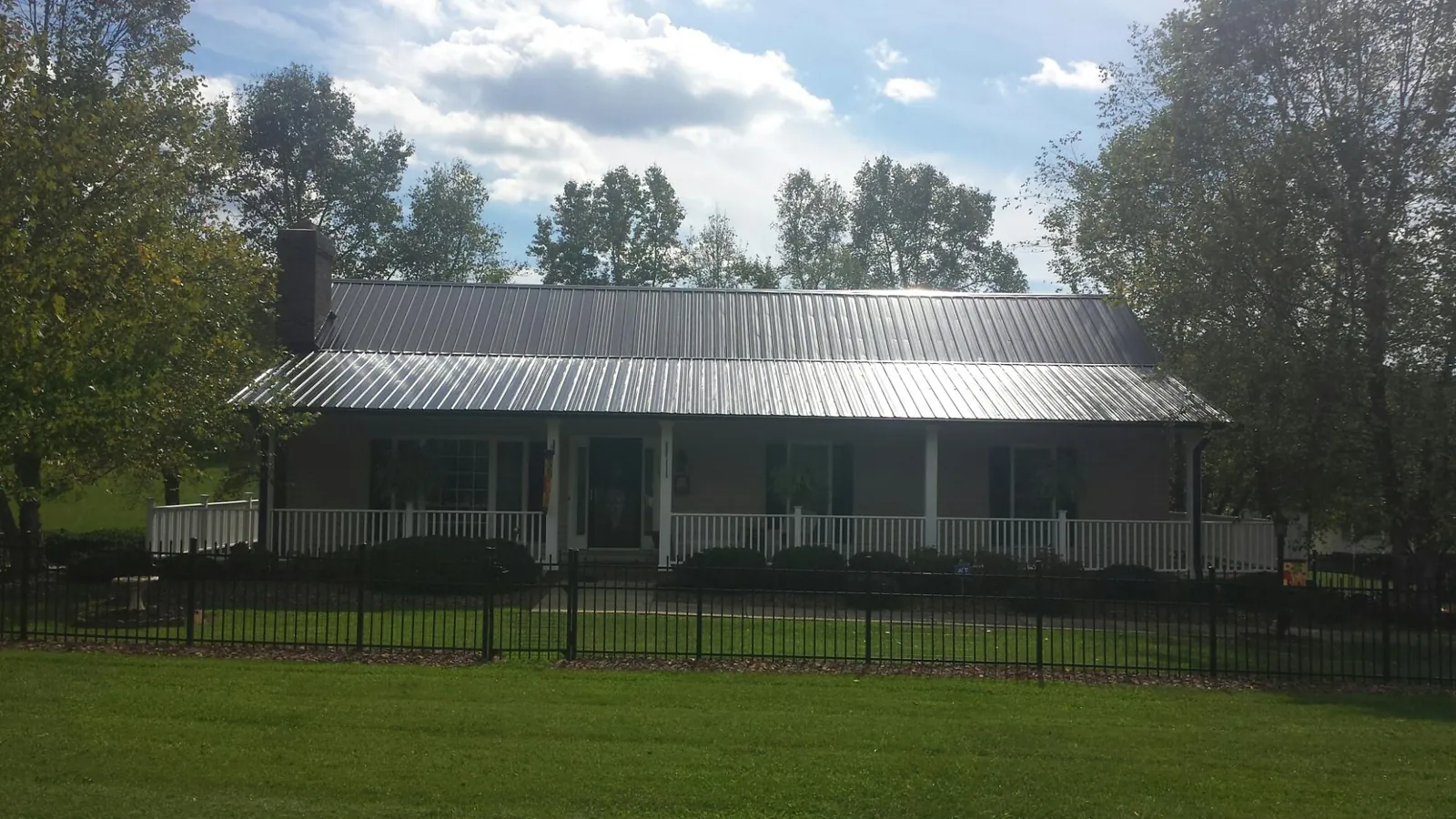 Gray metal roof on a brick ranch with a full width front porch — Gutter Guard Installation work by our crew in Burnside